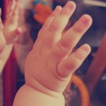 baby looking on glass - article featured image for baby stranger anxiety and daycare