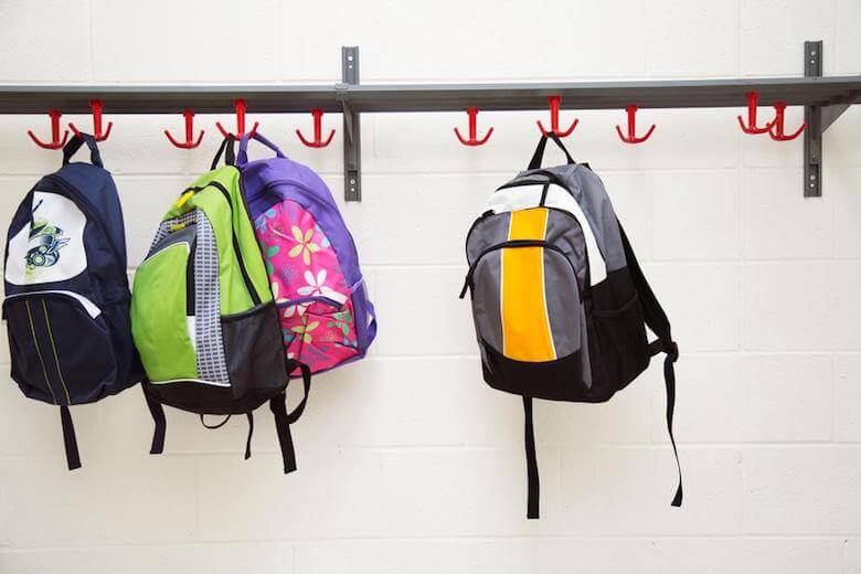 backpacks hanging on hooks - image for article on before and after school care benefits