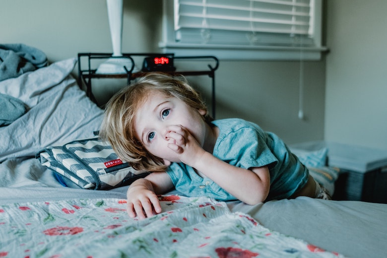 child not in bed leaning on bed - bedtime routine battle article image