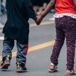 children holding hands street scene - neighbourhood walk ideas for daycare preschool article image