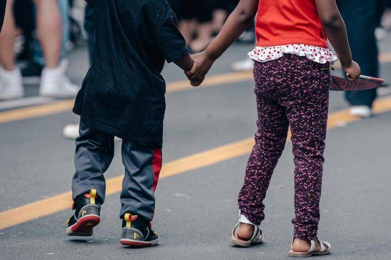children holding hands street scene - neighbourhood walk ideas for daycare preschool article image