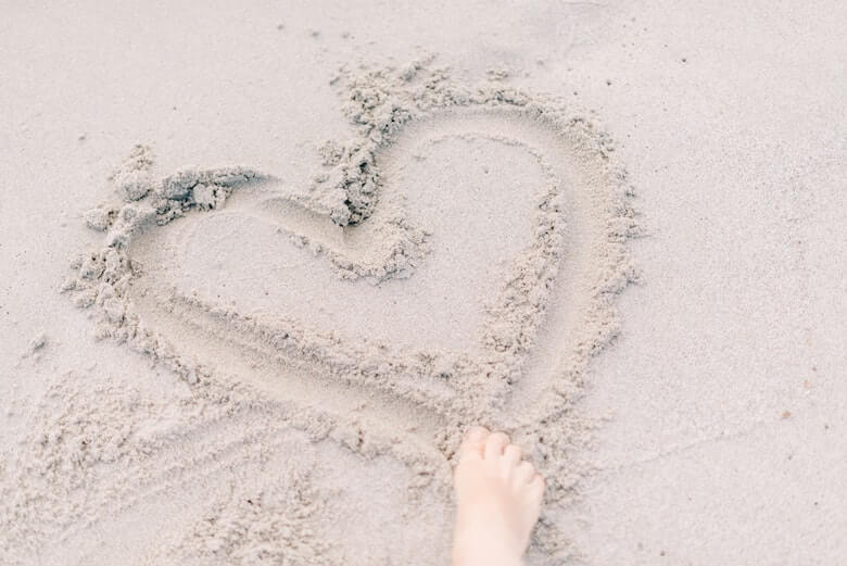 Drawing heart in sand as a sand activity
