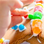 toddler fingers decorating gingerbread house with small pieces - fine motor skills article image