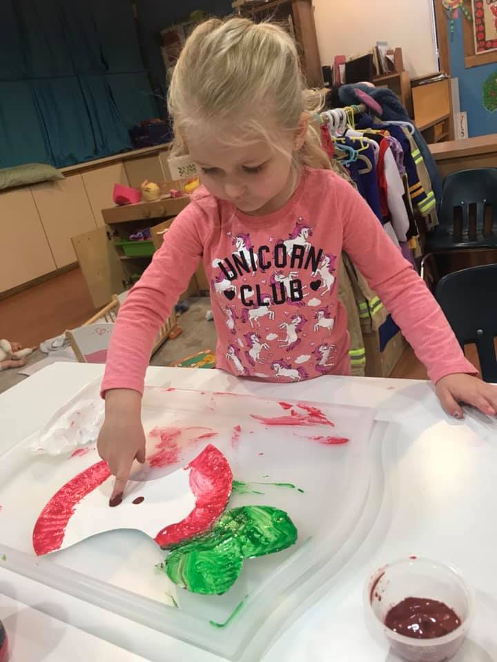 girl making paper apple craft and painting at preschool
