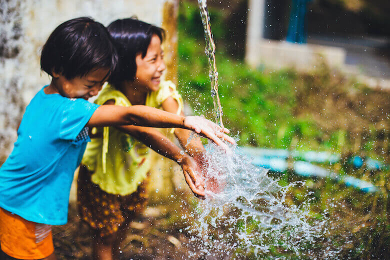 reasons to encourage play in early childhood - article featured image - girls playing with water