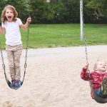 children balancing and pushing on swings depicting gross motor development in childhood