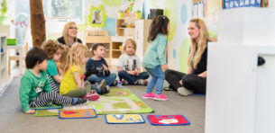 child interacting with teacher at daycare during circle time Early Childhood Education Careers