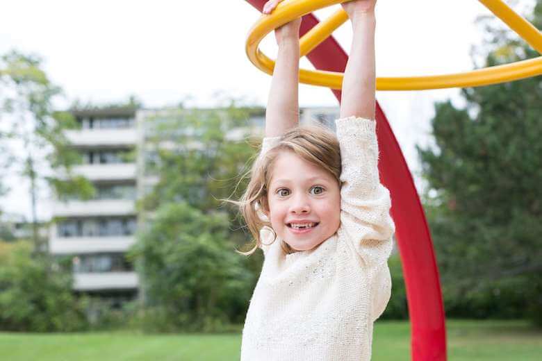 girl playing on monkey bars at a playground - teach emotional intelligence to kids article image