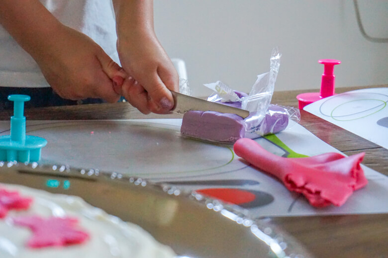 Child making cake decorations with fondant and child baking tools