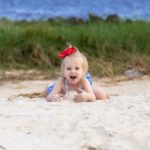 preschooler playing with sand at the beach - sand games and activities featured image