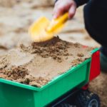 child playing with sand truck shovel - sensory idea for preschool