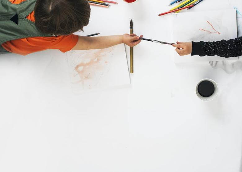 children sharing pencils at table - image for article on social competence in the early years